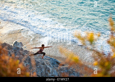 Eine junge Frau beim Yoga bei Sonnenuntergang in der Nähe des Strandes in Kalymnos, Griechenland Stockfoto