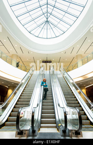 Business-Frau Reiten eine Rolltreppe im Bürogebäude Stockfoto