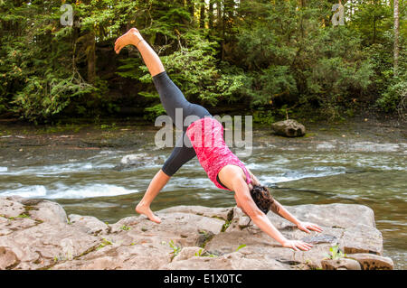 Nach unten vor Hund, drei beiniger Hund, Yoga-Pose im Freien vor einem Fluss, Courtenay, Britisch-Kolumbien, Kanada Stockfoto