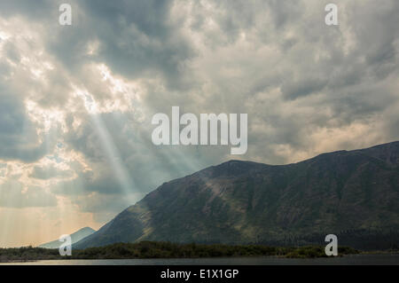 Tageslicht strömt durch die Wolken auf die Berge am südlichen Ende von Fish Lake, in der Nähe von Whitehorse, Yukon. Stockfoto