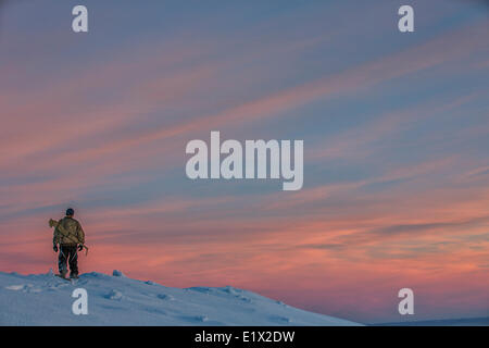 Mann zu Fuß in Schneeschuhen bei Sonnenuntergang auf der Oberseite Crow Mounatin, Old Crow, Yukon. Stockfoto