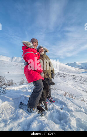 Brautpaar stehend mit ihrem Hund auf einem Hügel entlang der DempsterHighway, Yukon nach Schneeschuhwandern an der Spitze. Stockfoto