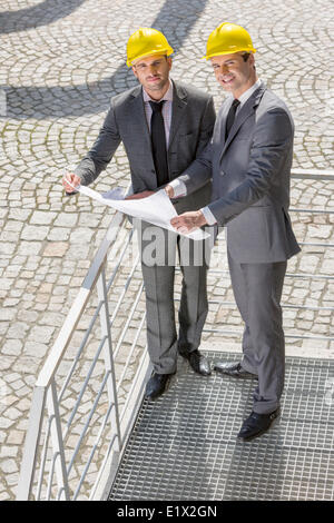 In voller Länge Portrait von Jungunternehmer mit Blaupause auf Treppe Stockfoto
