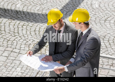 Junge Männchen Architekten analysieren Blaupause auf Baustelle Stockfoto