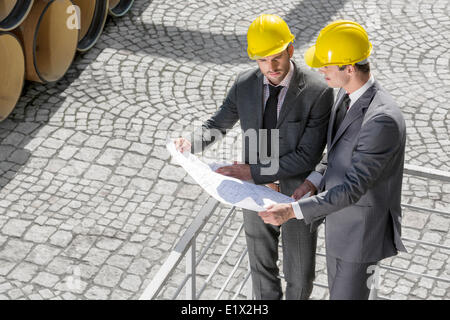 Erhöhte Ansicht der jungen männlichen Architekten Blaupause von Geländer zu untersuchen Stockfoto