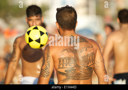 RIO DE JANEIRO, Brasilien - 18. Januar 2014: Brasilianische Mann mit Tattoos von Sehenswürdigkeiten der Stadt spielt eine Partie keepy uppy am Posto Nove Stockfoto