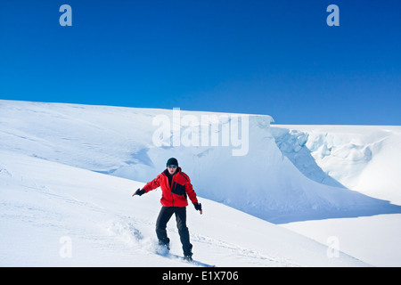 Mann geht auf Snowboard. Gletscher im Hintergrund. Antarktis Stockfoto