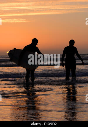 Ein paar entstehen aus dem Meer in der Abenddämmerung, die gegen der untergehende Sonne Stockfoto