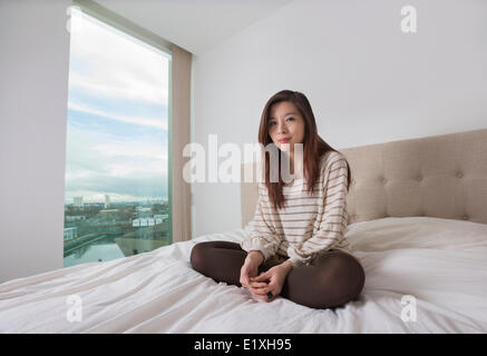 Porträt von schöne junge Frau sitzt auf Bett Stockfoto