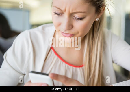 Junge Geschäftsfrau SMS über Handy im Büro Stockfoto