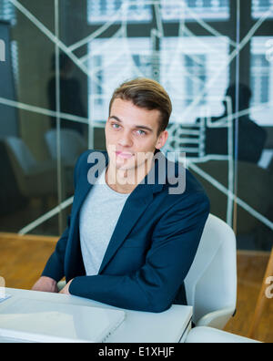 Porträt von zuversichtlich junger Geschäftsmann am Konferenztisch sitzen Stockfoto