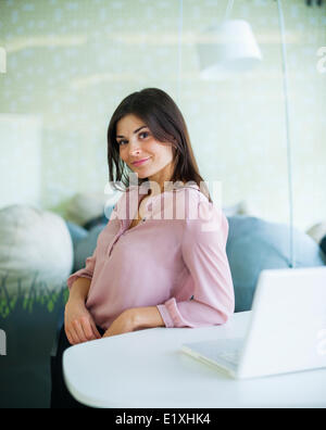 Porträt von überzeugt junge Geschäftsfrau lehnt sich am Bürotisch