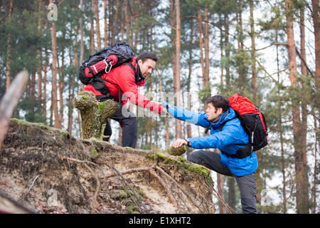 Junge männliche Wanderer Freund helfen, beim Wandern im Wald Stockfoto