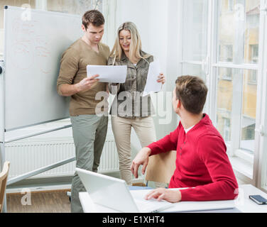 Unternehmer mit Blick auf Kollegen diskutieren über Dokumente in Office laptop Stockfoto