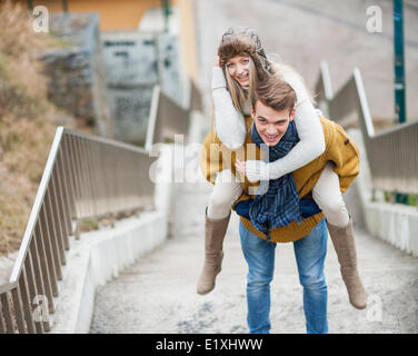 Porträt der lächelnde Frau wird von Mann auf Treppe piggybacked Stockfoto