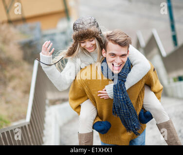 Porträt von fröhlicher Mensch Huckepack Frau auf der Treppe Stockfoto