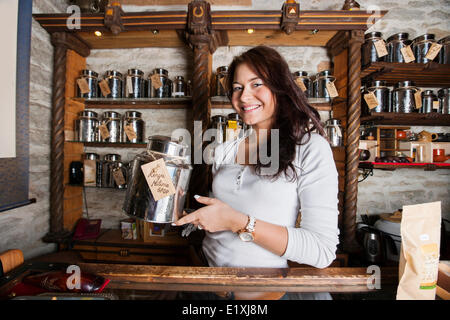 Porträt von lächelnden Verkäufer Tee Container im Shop anzeigen Stockfoto