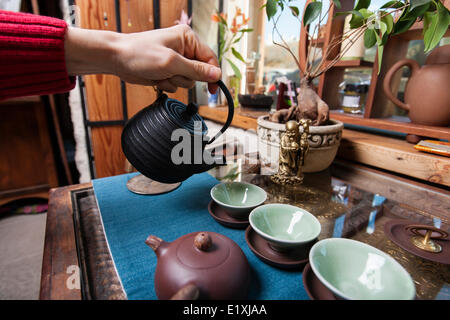 Männliche Hand Gießen Tee in Teetassen im store Stockfoto