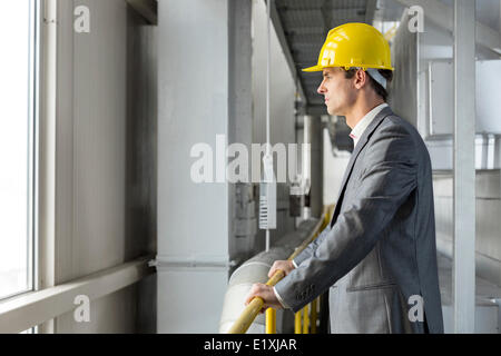 Seitenansicht des nachdenklichen männlichen Architekten stehen durch Geländer in der Industrie Stockfoto