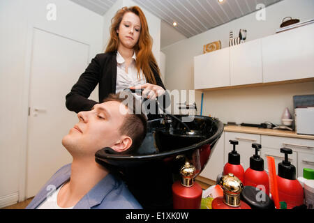 Weibliche Friseur Haarewaschen männlicher Kunde im shop Stockfoto