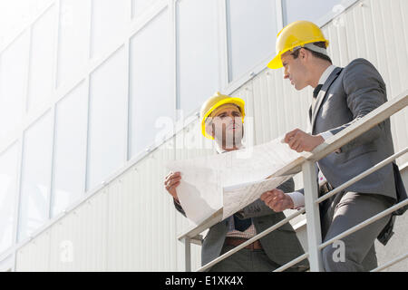 Voller Länge der jungen Unternehmer diskutieren über Blueprint auf Treppe Stockfoto