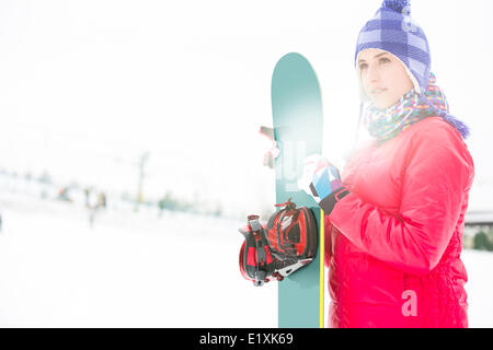 Schöne junge Frau in warme Kleidung hält Snowboard im winter Stockfoto