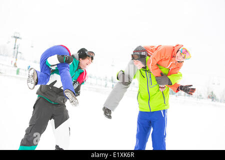 Verspielte junge Paare genießen im Schnee Stockfoto