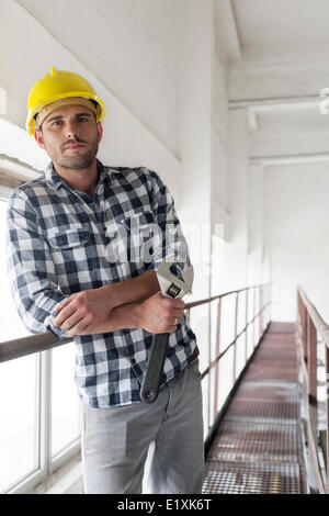 Junge männliche Arbeiter mit Schraubenschlüssel stützte sich auf großen industriellen Ventil Stockfoto