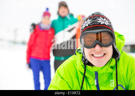 Porträt von lächelnden jungen Mann mit Freunden im Hintergrund während des Winters Stockfoto