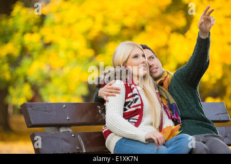 Junger Mann zeigt etwas zu Frau beim gestikulieren im Park im Herbst