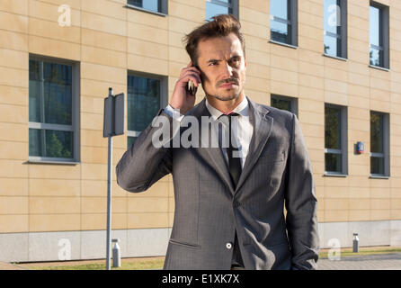 Geschäftsmann mit Handy gegen Bürogebäude Stockfoto