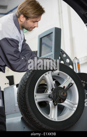 Bild des Kfz Mechaniker Reparatur Auto-Rad in Werkstatt zugeschnitten Stockfoto