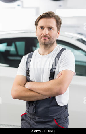 Porträt von zuversichtlich männlichen Mechaniker stehend Arme gekreuzt in Werkstatt Stockfoto