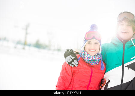 Fröhliches junges Paar stehende Arm um im Schnee Stockfoto