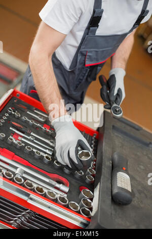 Erhöhte Ansicht von männlichen Mechaniker Vermittlung von Werkzeugen in Schublade auf Auto-Werkstatt Stockfoto