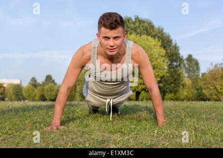 Porträt des jungen Mannes tun Liegestütze im park Stockfoto