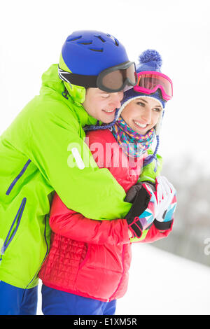 Glücklich liebende Mann umarmt Frau im Schnee Stockfoto