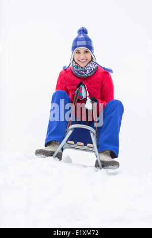 In voller Länge Portrait von glückliche junge Frau Schlittenfahrt im Schnee genießen Stockfoto