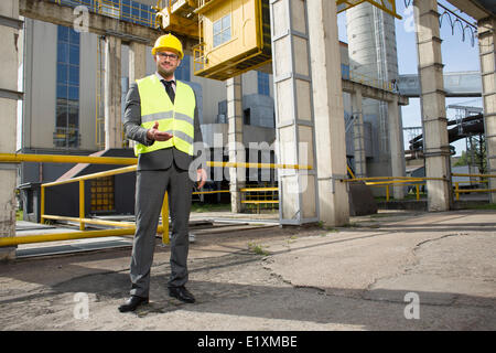 In voller Länge Portrait von zuversichtlich männlichen Ingenieur gestikulieren außerhalb Industrie Stockfoto