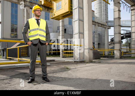 Volle Länge des jungen männlichen Ingenieur mit Händen in den Taschen stehen außen Industrie Stockfoto