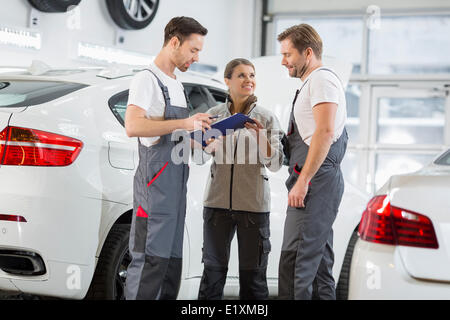 Automechaniker diskutieren über Zwischenablage in Autowerkstatt Stockfoto