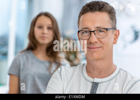 Porträt von lächelnden Mann mit Tochter im Hintergrund zu Hause stehen Stockfoto