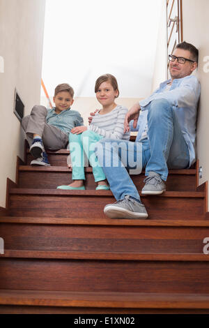 In voller Länge Portrait von Vater und Kinder sitzen auf Schritte zu Hause Stockfoto