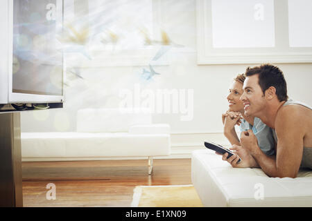 Glückliches junges Paar vor dem Fernseher zu Hause Stockfoto