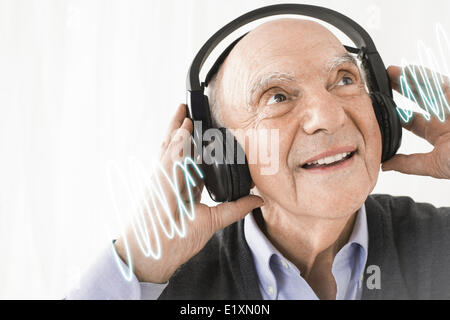 Fröhlicher senior Mensch Musik hören über Kopfhörer vor weißem Hintergrund Stockfoto