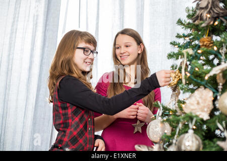 Schwestern, die Dekoration am Weihnachtsbaum zu Hause Stockfoto