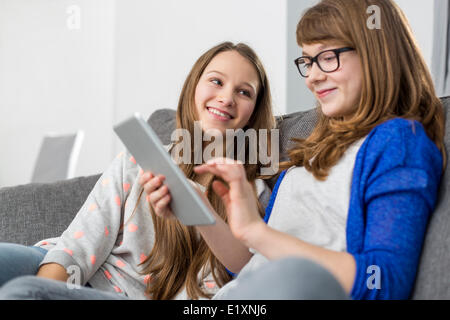 Glückliches Mädchen Blick auf Schwester mit digital-Tablette zu Hause auf sofa Stockfoto