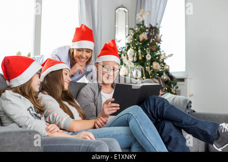 Vierköpfige Familie Buch im Wohnzimmer in der Weihnachtszeit Stockfoto