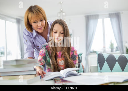 Mutter Mitarbeitende Tochter in Hausaufgaben am Tisch Stockfoto