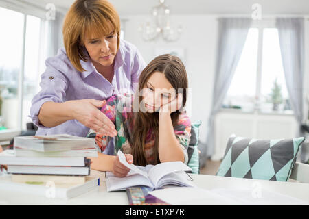 Studium zu Hause gelangweilt Mädchen bei Mutter Stockfoto